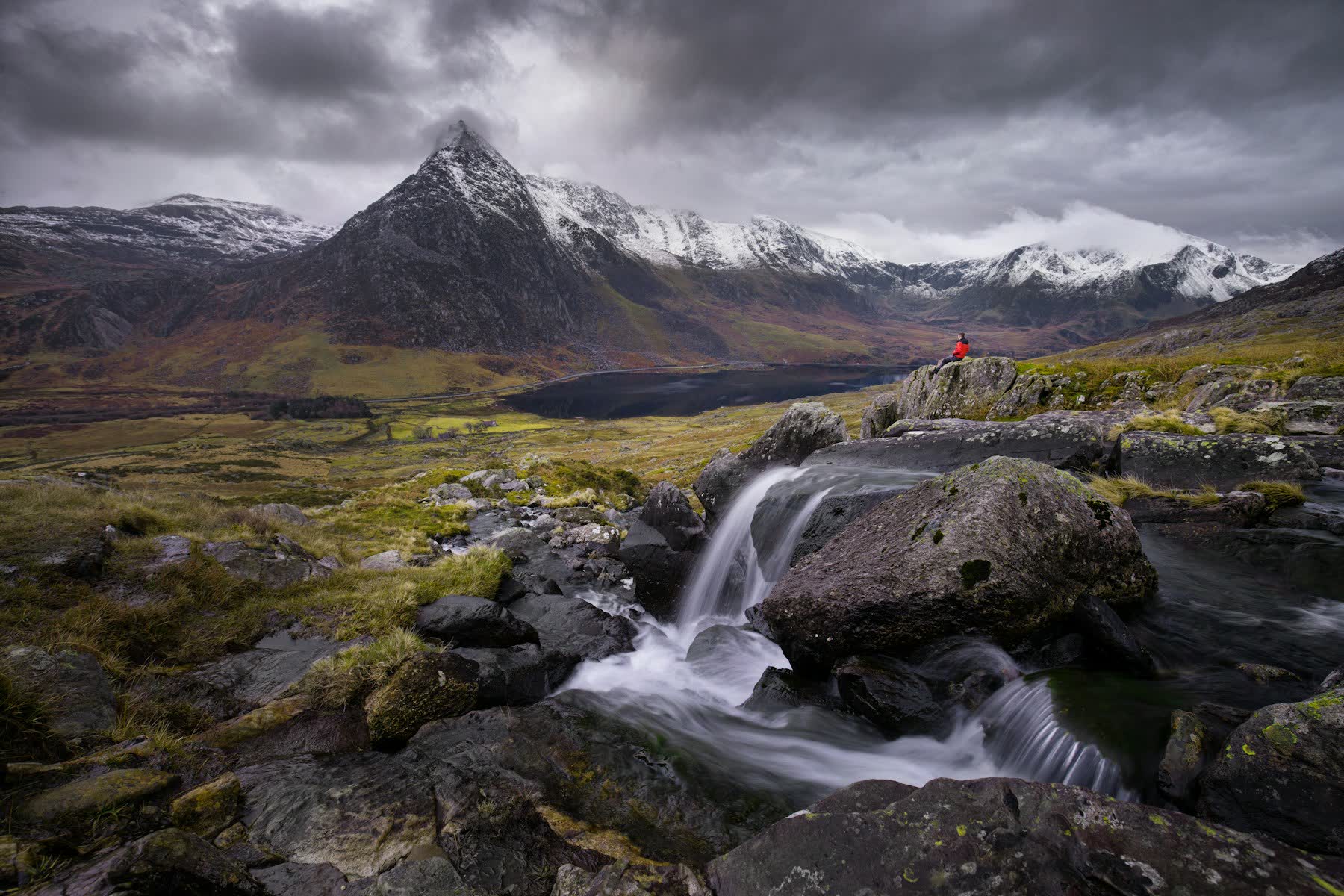 Hiker resting above a waterfall in the Welsh mountains on a Revival Retreats trip
